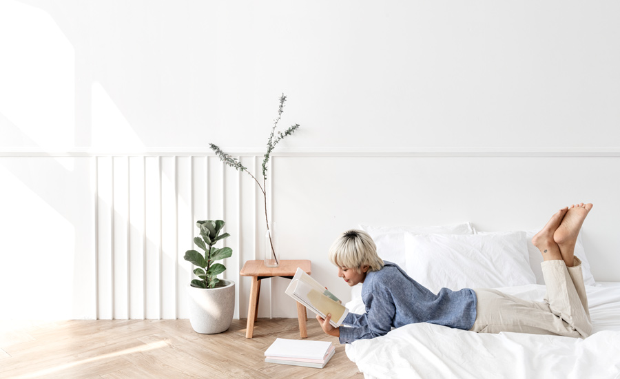 Blond haired asian woman reading a book on a mattress